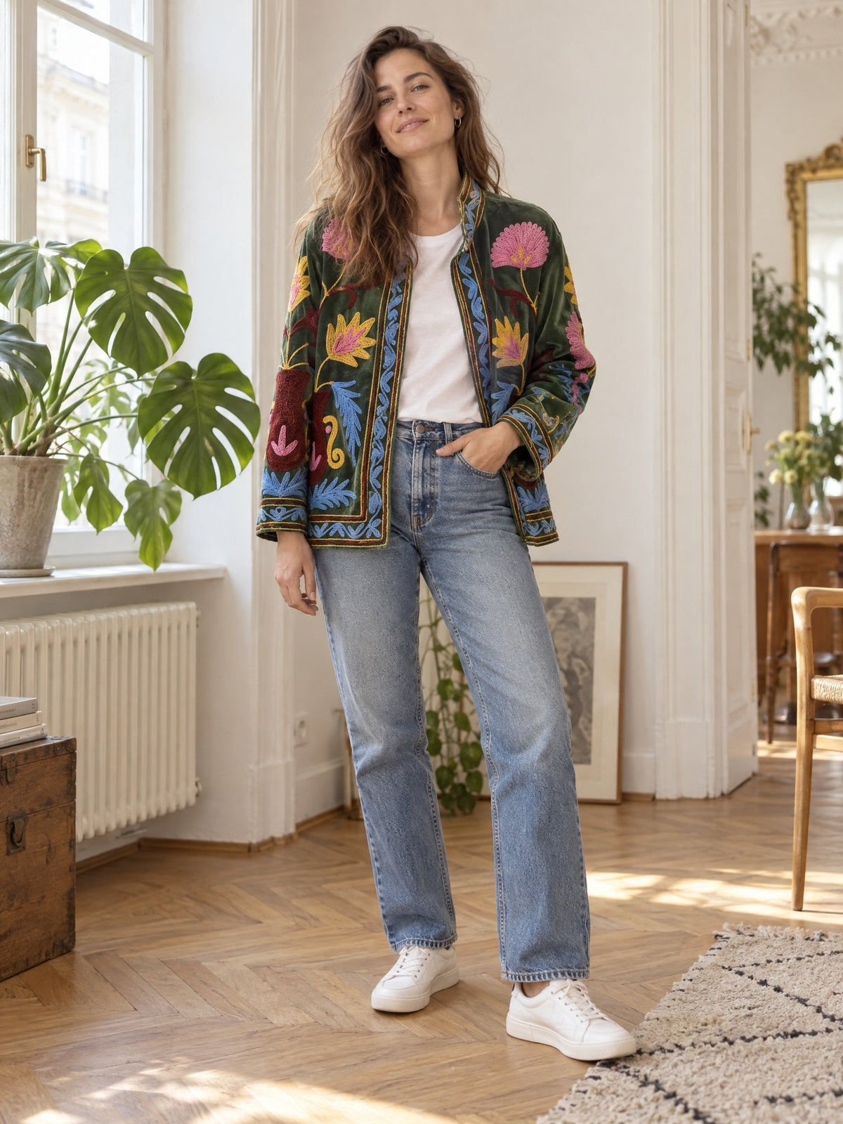 Frau trägt Suzani Velvet Jacket Forest Lotus mit Kettenstich-Stickerei offen über weißem T-Shirt und Jeans