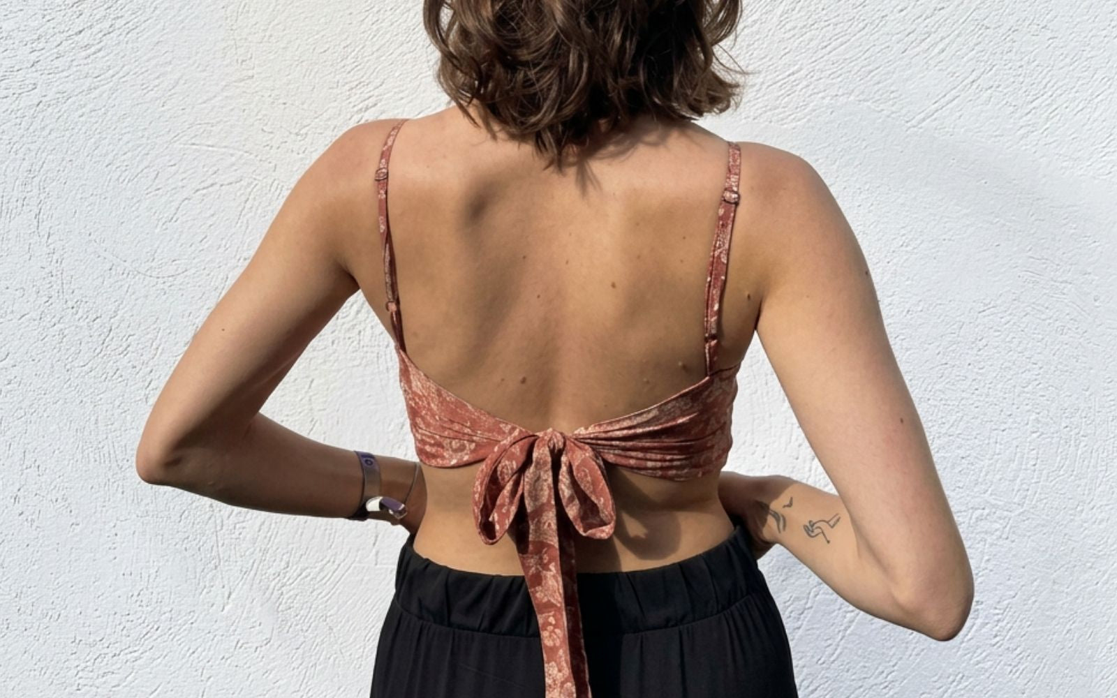 Rückansicht: Model trägt Wickeltop aus rostrotem Sari-Stoff mit Blumenmuster, im Rücken gebunden mit Schleife