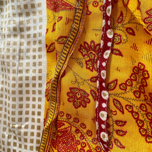 Stoffdetail: upcycelter Sari-Stoff in Gelb mit rotem Blumen-Paisley und Gitterkaro-Bordüre