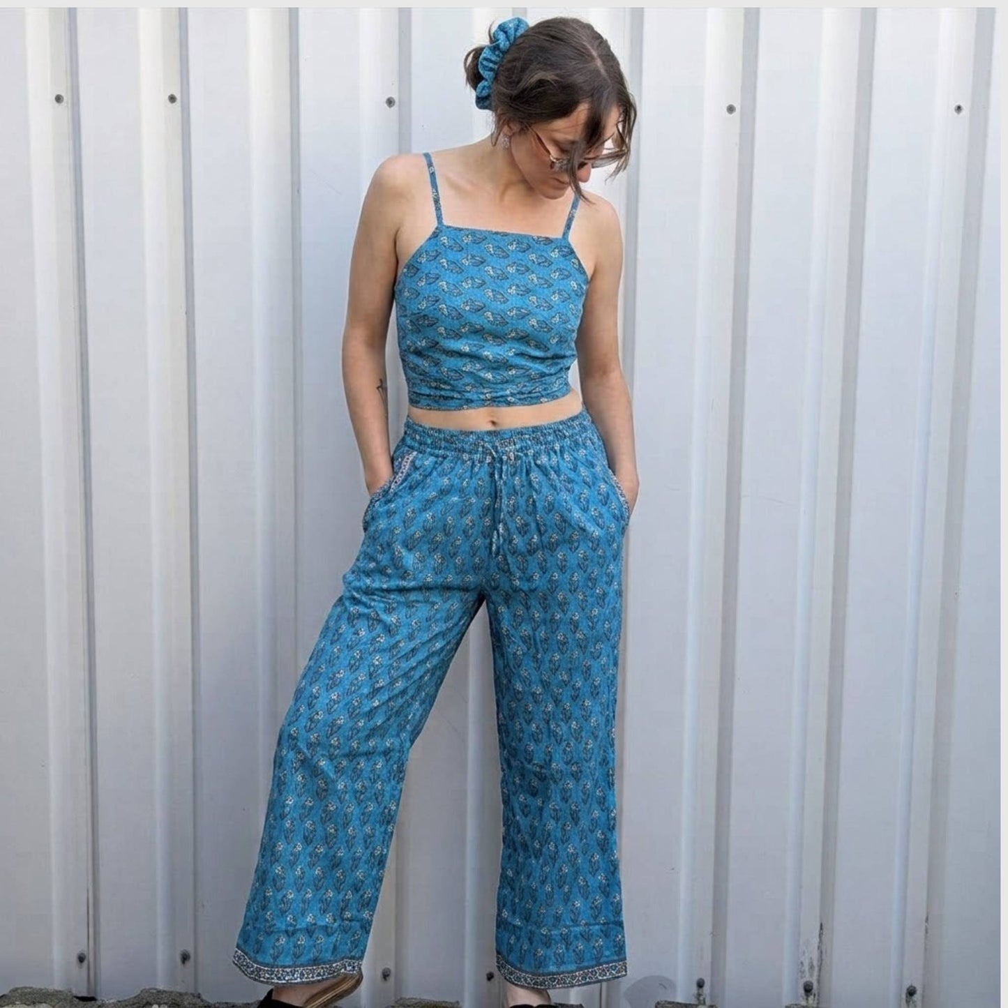 Model trägt Upcycled Set aus Wickeltop und Palazzo-Hose aus Sari-Stoff in Türkis mit Blumen-Print in Creme und Orange