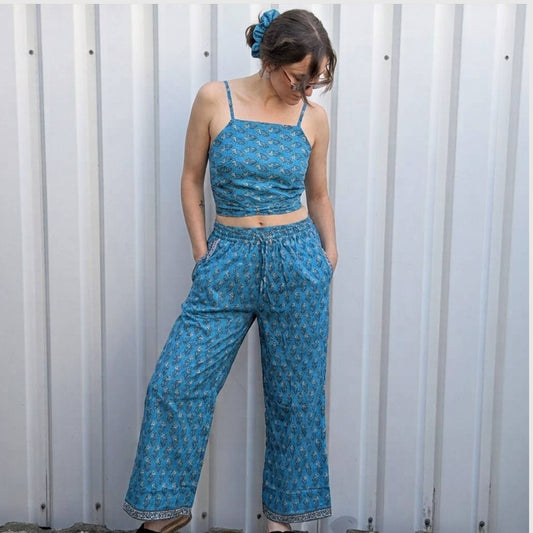Model trägt Upcycled Set aus Wickeltop und Palazzo-Hose aus Sari-Stoff in Türkis mit Blumen-Print in Creme und Orange