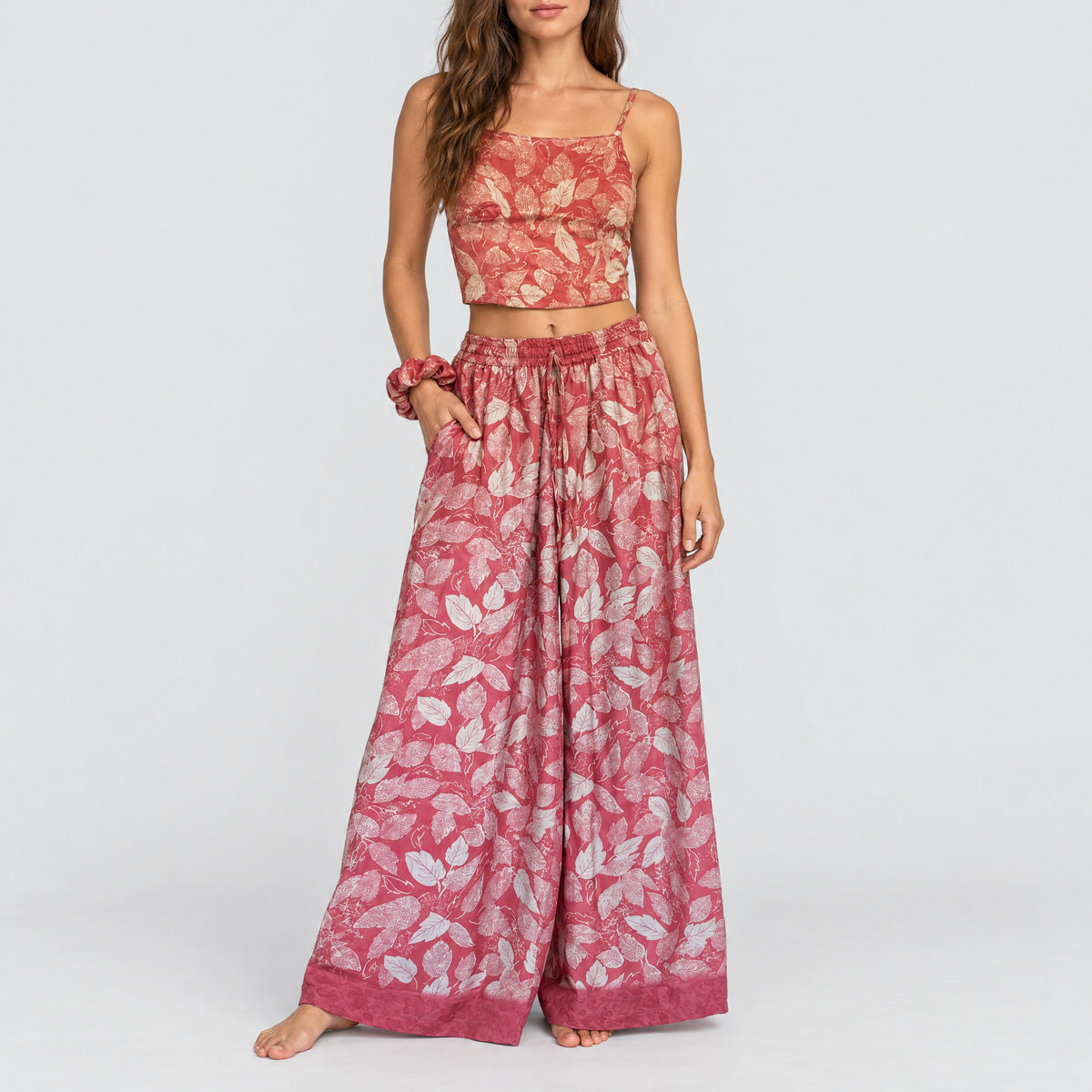Model trägt Upcycled Set aus Wickeltop und Palazzo-Hose aus Sari-Stoff in Rosa & Rot